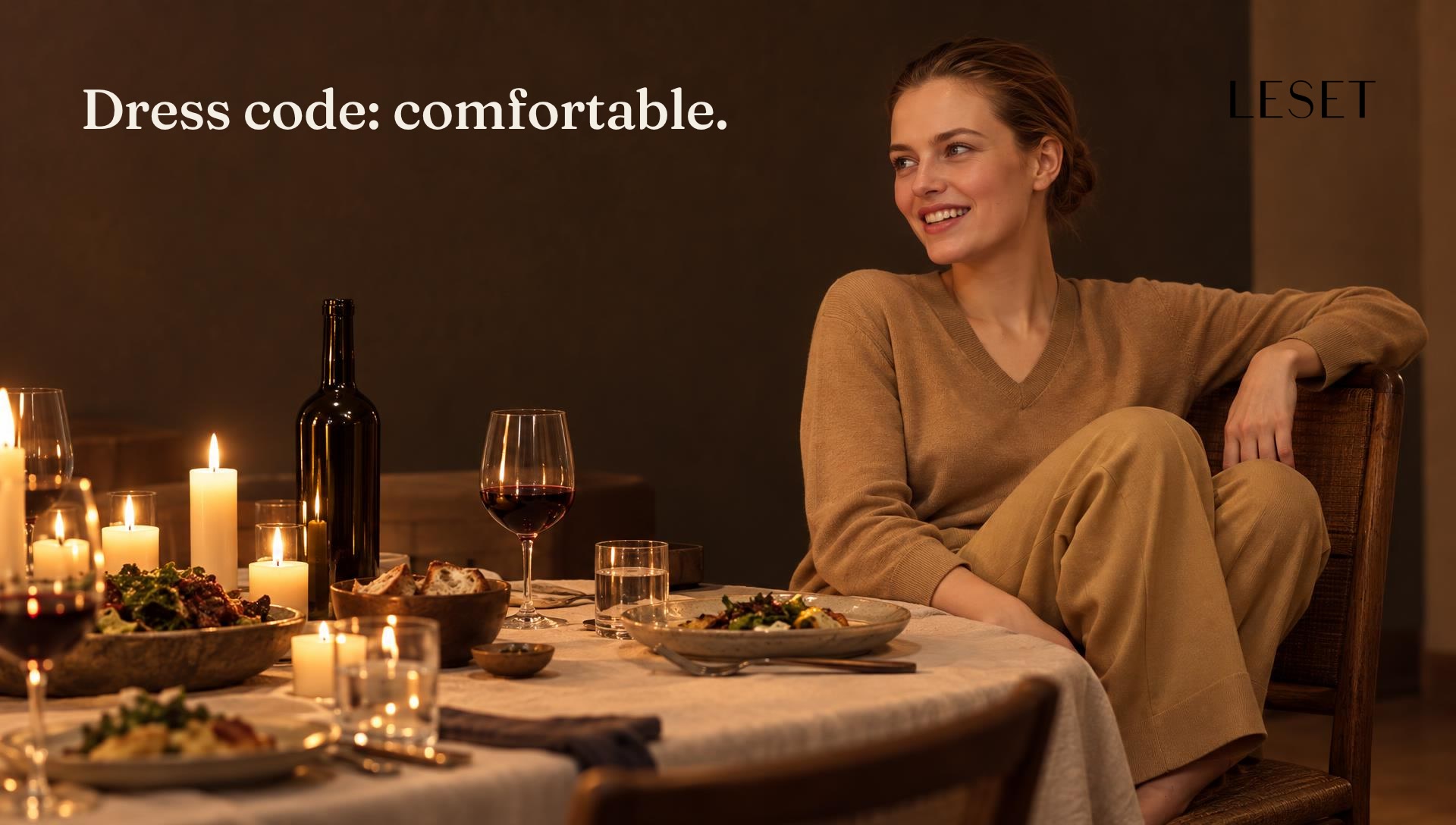 A woman at a candlelit dinner with her feet tucked up on the chair